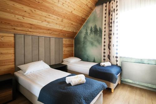 two beds in a room with wooden walls and a window at Słoneczne Chatki in Knurów