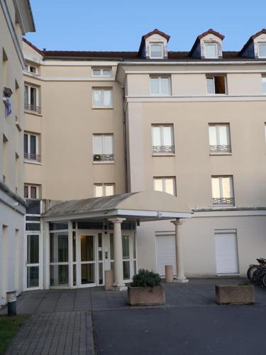 - un grand bâtiment blanc avec une terrasse en face dans l'établissement Pretty little flat near from DisneyLand Paris, à Bussy-Saint-Georges