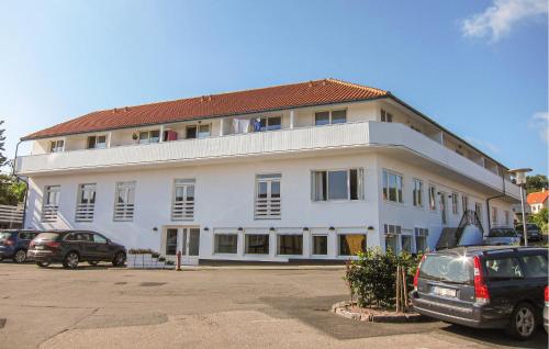 a white building with cars parked in a parking lot at Stunning Apartment In Gudhjem in Gudhjem