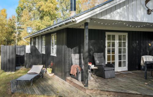 a black house with two chairs and a table on a deck at 3 Bedroom Amazing Home In Væggerløse in Marielyst