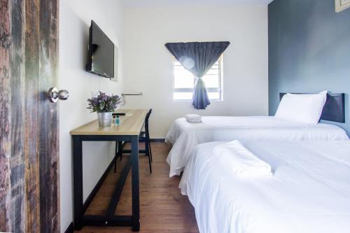 a room with two beds and a table and a window at Plumeria 5BR Garden House by uBook in Butterworth