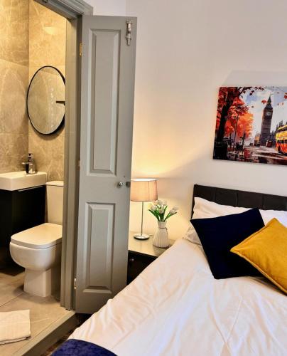 a bedroom with a bed and a toilet and a sink at Camden Luxury Studio Flats and En-Suit Rooms in London