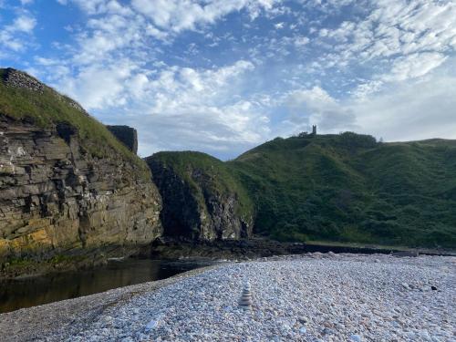 a rocky beach with a castle on top of a mountain at Ceol-na-Mara in Berriedale