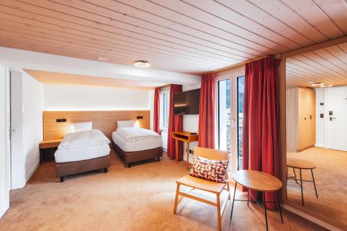 a hotel room with two beds and a table at Hotel Kreuz & Post Grindelwald in Grindelwald