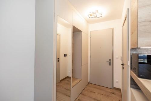 a small hallway with white walls and wood floors at ALURE RESIDENCES 9 & 24h self check-in, private parking in front of the apartment building included, new building, terrace, the apartment building has its own park with a lake and outdoor fitness, children's playground, CITY CENTER in Banská Bystrica