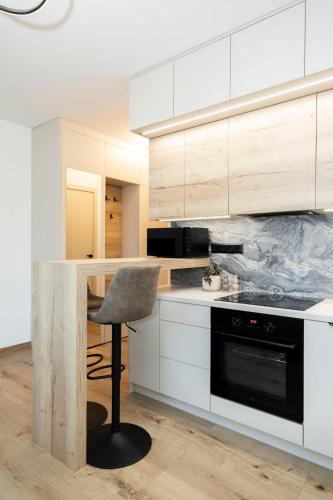 a kitchen with white cabinets and a chair in it at ALURE RESIDENCES 9 & 24h self check-in, private parking in front of the apartment building included, new building, terrace, the apartment building has its own park with a lake and outdoor fitness, children's playground, CITY CENTER in Banská Bystrica