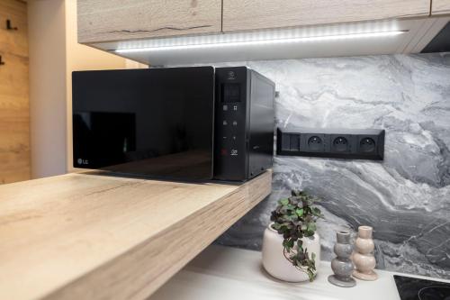 a black microwave on a counter in a kitchen at ALURE RESIDENCES 9 & 24h self check-in, private parking in front of the apartment building included, new building, terrace, the apartment building has its own park with a lake and outdoor fitness, children's playground, CITY CENTER in Banská Bystrica