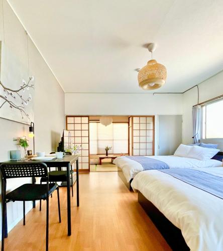 a bedroom with two beds and a table and a desk at OMOTENASHI STAY OSAKA 41m2 1LDK 十三駅徒歩1分 梅田2分 神戸京都アクセス良好 和室のある家 in Osaka