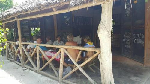 a group of people sitting outside of a restaurant at SHADRACK BackPackers in Nungwi