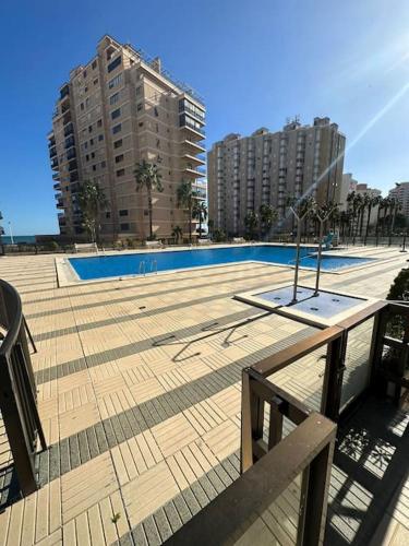 an empty swimming pool in a city with tall buildings at Apto con encanto en primera línea de playa , Cullera in Cullera