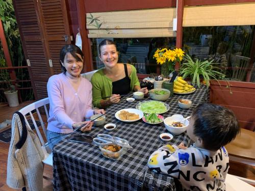 two women and a boy sitting at a table with food at Nắng Xinh Homestay in Xuan An