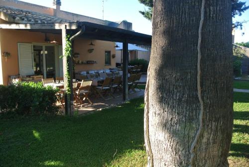 ein Baum neben einem Haus mit einem Tisch und Stühlen in der Unterkunft Villa Carlotta Resort in San Leone