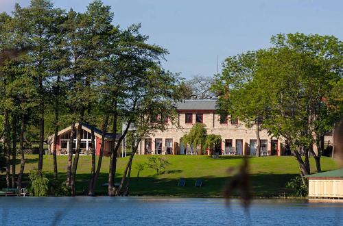 a person walking in front of a building next to a lake at Zwergtaucher - Ferienwohnung mit Balkon, Seeblick & Freizeitangeboten am See in Jabel