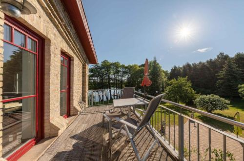 a deck with a chair on the side of a house at Zwergtaucher - Ferienwohnung mit Balkon, Seeblick & Freizeitangeboten am See in Jabel