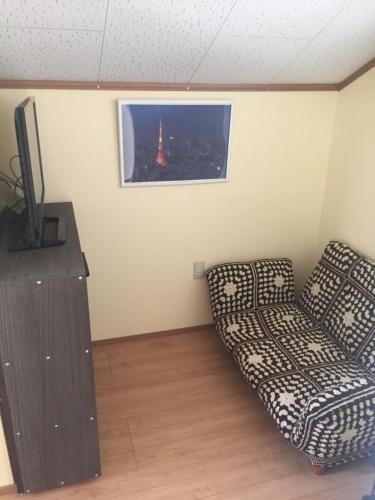 a living room with a couch and a television at Guest house mochilero onomichi in Onomichi
