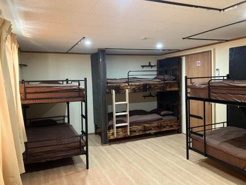 a room with three bunk beds in a room at Guest house mochilero onomichi in Onomichi