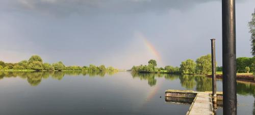 a river with a rainbow in the distance with a dock at Sientjes Boetiekhotel in Kerkdriel