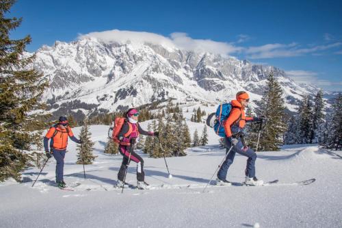three people on skis on a snow covered mountain at AlpenParks Hotel Maria Alm in Maria Alm am Steinernen Meer