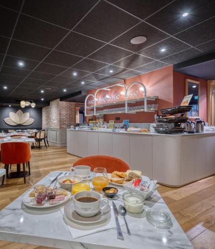 a table with breakfast food on it in a restaurant at Brit Hotel Les Voyageurs in Loudéac