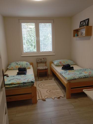 a bedroom with two beds and a chair and two windows at Dovolenkový dom Nika in Vinné