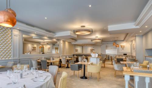 a restaurant with tables and chairs in a room at Brit Hotel Les Voyageurs in Loudéac