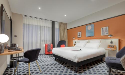 a hotel room with a bed and a desk and chairs at Brit Hotel Les Voyageurs in Loudéac