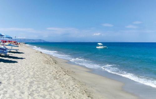 a boat in the ocean next to a beach at 1 Bedroom Amazing Apartment In Staletti in Stalettì
