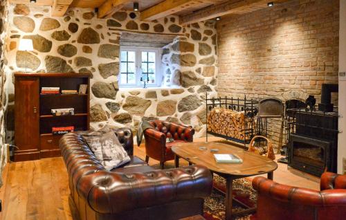 a living room with leather furniture and a stone wall at Lovely Home In Sallerup With Wifi in Hörby