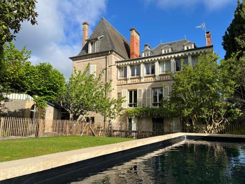 an old house with a pond in front of it at Demeure de Flore - Hôtel Particulier au Cœur de Brive comprenant 8 appartements de charme in Brive-la-Gaillarde