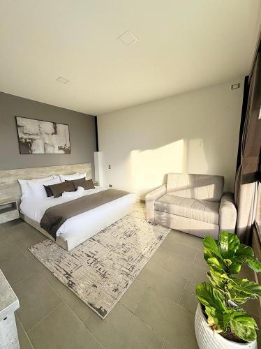 a bedroom with a bed and a chair and a couch at Rooca Habitat Guatape in Guatapé