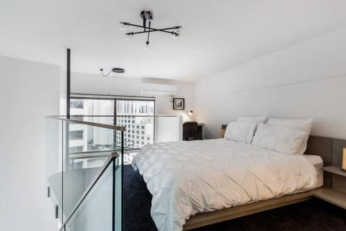 a white bedroom with a bed and a glass staircase at KozyGuru Sydney CBD Harbor View Loft with Parking in Sydney