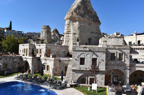 a building with a pool and chairs in front of it at Göreme Cave Suites in Goreme