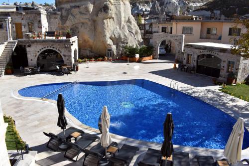 a swimming pool with chaise lounge chairs and umbrellas at Göreme Cave Suites in Goreme