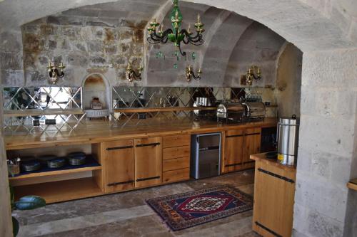 a kitchen with wooden cabinets and a stone wall at Göreme Cave Suites in Goreme