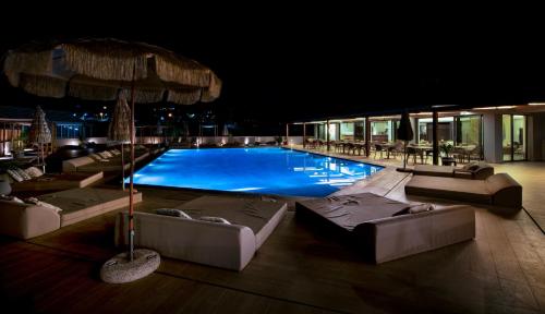 a large swimming pool with couches and umbrellas at Mare Village Hotel in Georgioupolis