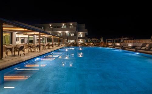 a swimming pool at night with tables and chairs at Mare Village Hotel in Georgioupolis