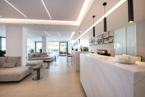 a lobby with a bar and a couch and chairs at Mare Village Hotel in Georgioupolis