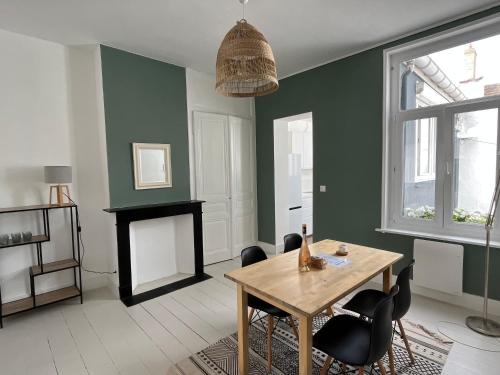 un salon avec une table et des chaises et une cheminée dans l'établissement Maison plein cœur de Malo-les-Bains - Proximité plage et commerces, à Dunkerque