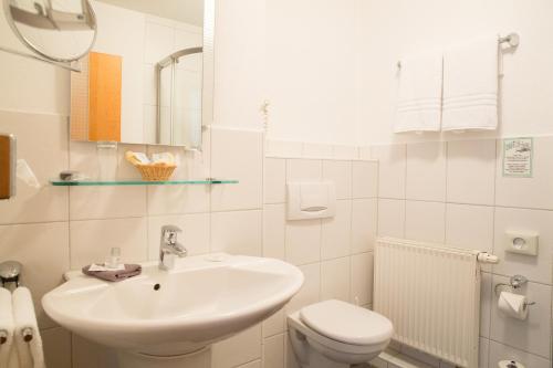 a white bathroom with a sink and a toilet at Hotel Pfeffermühle in Siegen