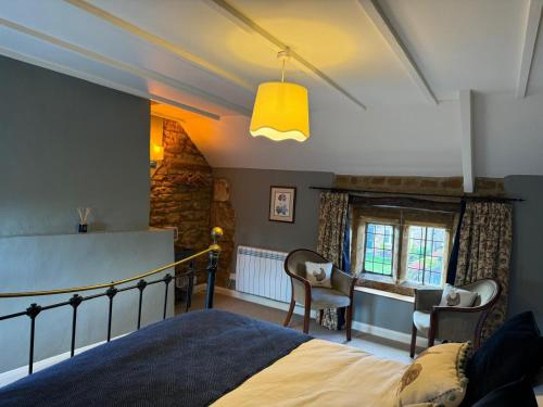 a bedroom with a bed and two chairs and a window at The Royal Oak in Eydon