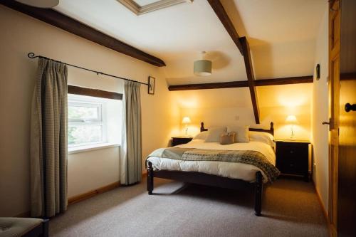 a bedroom with a large bed with a window at Ash Cottage - Escape to Pembrokeshire Cottage with Pool & Sauna in HAW