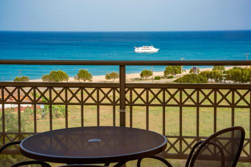 a table and chairs on a balcony with a boat in the ocean at Crystal Palace - Vista in Skala Kefalonias
