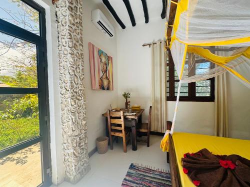 a bedroom with a bed and a dining room with a table at Z-Breeze Zanzibar in Kiwengwa