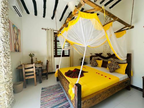 a bedroom with a yellow bed with an umbrella at Z-Breeze Zanzibar in Kiwengwa