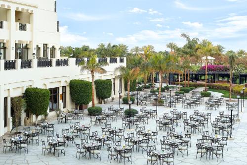 an outdoor patio with tables and chairs and palm trees at Steigenberger Aldau Beach Hotel in Hurghada