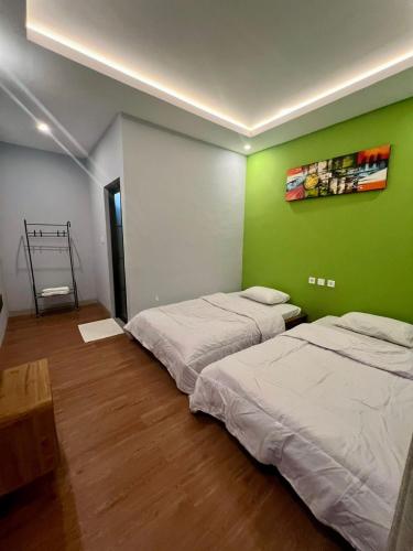 two beds in a room with a green wall at Makarma Resort Lombok in Senggigi 