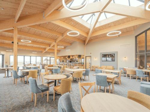 a dining room with tables and chairs and windows at Ivy Caravan 2 at Queensberry Bay Leisure Park in Annan