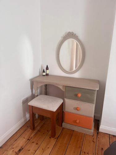 a dressing table with a mirror and a stool at Holly Tree Cottage in Glastonbury in Glastonbury