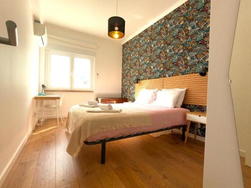 a bedroom with a bed with a floral accent wall at Lisboa T3 moderno Benfica in Lisbon