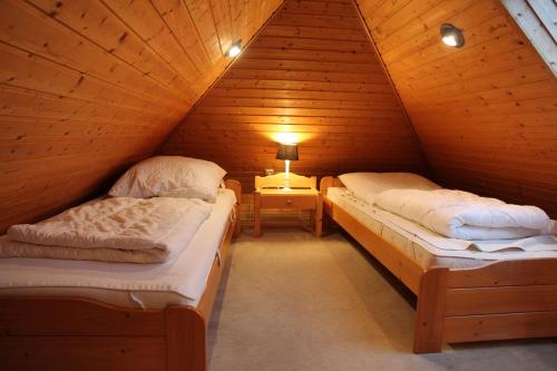 two beds in a wooden attic room with a lamp at Seerobbe in Norddeich